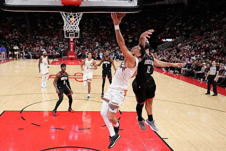 Phoenix Suns' Devin Booker (1) goes up for a shot as Houston Rockets' Steven Adams (12) defends during the second half of an NBA basketball game in Houston. - | Photo: AP/David J. Phillip
