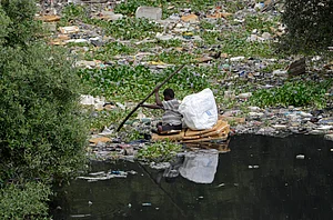 IMAGO / NurPhoto : A man paddles a makeshift raft made of thermocol sheets through the polluted waters of the Mithi River in Mumbai, India, on July 1, 2025. The river, which flows through the city s industrial and residential zones, remains heavily contaminated due to untreated sewage and solid waste dumping, posing serious health and environmental risks.