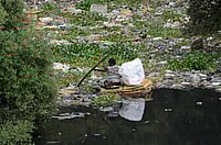 IMAGO / NurPhoto : A man paddles a makeshift raft made of thermocol sheets through the polluted waters of the Mithi River in Mumbai, India, on July 1, 2025. The river, which flows through the city s industrial and residential zones, remains heavily contaminated due to untreated sewage and solid waste dumping, posing serious health and environmental risks.