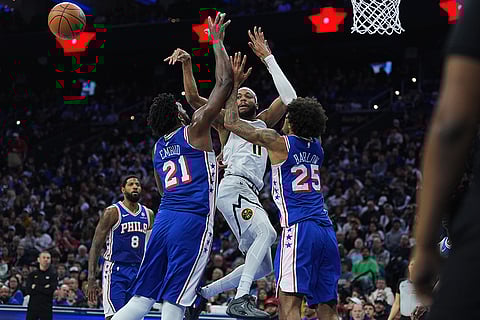 Denver Nuggets' Bruce Brown (11) passes the ball past Philadelphia 76ers' Joel Embiid (21) and Dominick Barlow (25) during the second half of an NBA basketball game in Philadelphia.