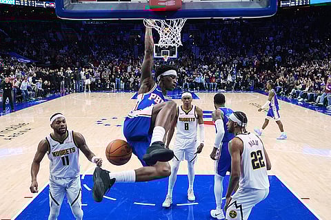 Philadelphia 76ers' Vj Edgecombe, center, hangs from the rim after dunking against the Denver Nuggets during the overtime of an NBA basketball game in Philadelphia. 