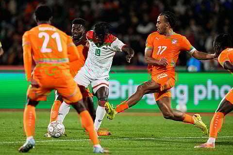 Ivory Coast's Guela Doue, right, challenges Burkina Faso's Georgi Minoungou during the Africa Cup of Nations best of 16 soccer match between Ivory Coast and Burkina Faso in Marrakech, Morocco.