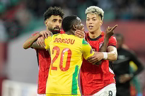 Benin's Jodel Dossou, center, argues with Egypt's head coach Hossam Hassan during the Africa Cup of Nations round of 16 soccer match between Egypt and Benin in Agadir, Morocco.