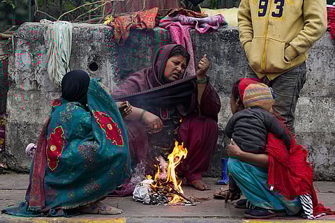 Women warm themselves near a small fire amid cold winter weather on a roadside, in New Delhi.