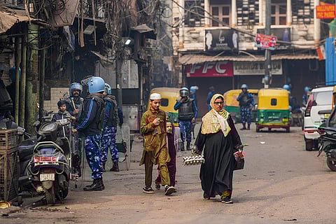 A woman carries groceries as security personnel keep vigil amid Friday prayers following an anti-encroachment drive near the Faiz-e-Elahi mosque on the intervening night of Tuesday and Wednesday that triggered violence, opposite the Turkman Gate area, in New Delhi.