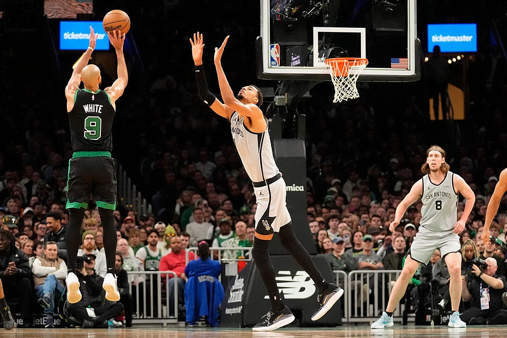 Boston Celtics guard Derrick White (9) shoots over San Antonio Spurs forward Victor Wembanyama during the second half of an NBA basketball game in Boston. - | Photo: AP/Robert F. Bukaty