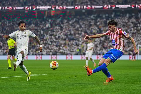 Atletico Madrid's Matteo Ruggeri kicks the ball next to Real Madrid's Rodrygo during the Spanish Super Cup semifinal soccer match at King Abdullah Sports City Stadium in Jeddah, Saudi Arabia.