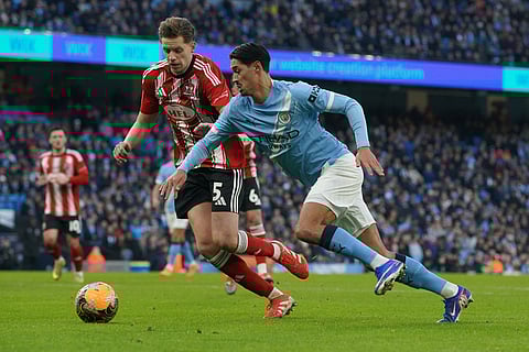 Manchester City's Tijjani Reijnders, right, and Exeter's Jack Fitzwater fight for the ball during the FA Cup third round match between Manchetster City and Exeter in Manchester, England.