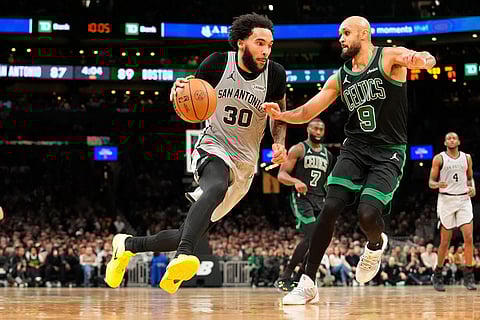 San Antonio Spurs forward Julian Champagnie (30) drives against Boston Celtics guard Derrick White (9) during the second half of an NBA basketball game in Boston.