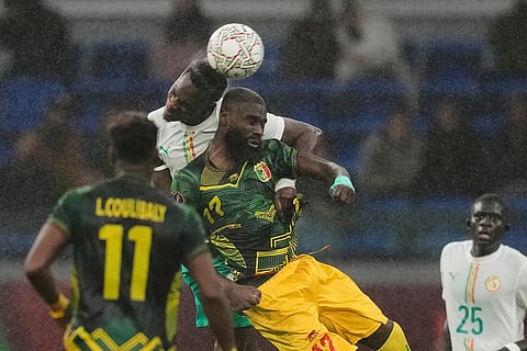 Senegal's Lamine Camara, background, and Mali's Lassine Sinayoko jump for the ball during the Africa Cup of Nations quarterfinal soccer match between Senegal and Mali in Tangier, Morocco.