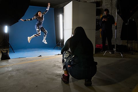 Skier Jackie Wiles, left, of Portland, jumps for a fun photo being taken by skier Bella Wright, 28, of Salt Lake City, between shoots by the team photographer in a makeshift photo studio in an underground parking garage at Copper Mountain, Colo.