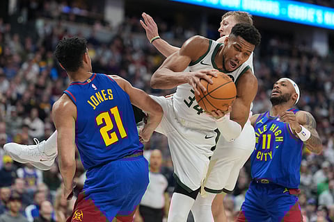 Milwaukee Bucks forward Giannis Antetokounmpo, center, pulls in a rebound between Denver Nuggets forward Spencer Jones, left, and guard Bruce Brown in the second half of an NBA basketball game in Denver.