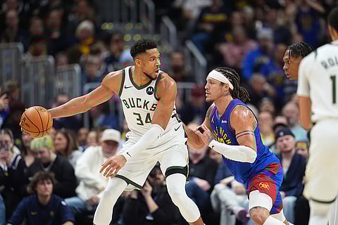 Milwaukee Bucks forward Giannis Antetokounmpo, left, looks to pass the ball as Denver Nuggets forward Aaron Gordon defends in the second half of an NBA basketball game in Denver.
