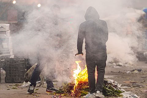People warm themselves by a small fire as cold weather conditions prevail, at Sahibabad Sabzi Mandi, in Ghaziabad. Delhi recorded its coldest January morning in three years on Tuesday as the minimum temperature dropped to 3 degrees Celsius, the India Meteorological Department (IMD) said.