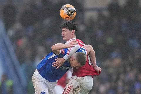 Portsmouth's Colby Bishop, left, and Arsenal's Christian Norgaard fight for the ball during the FA Cup third round soccer match between Portsmouth and Arsenal in Portsmouth, England.