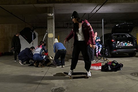 Skier Jackie Wiles, of Portland, Ore., skateboards while waiting for her turn for a photo shoot by the team photographer in a makeshift photo studio in an underground parking garage at Copper Mountain, Colo.