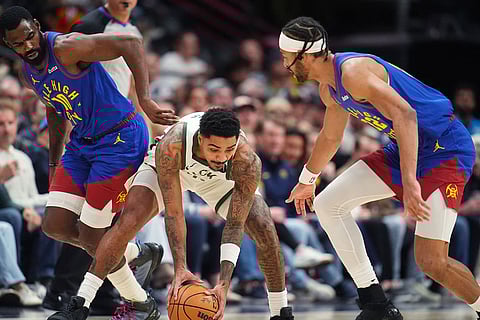 Milwaukee Bucks guard Gary Harris, center, collects a loose ball between Denver Nuggets guard Tim Hardaway Jr., left, and center Zeke Nnaji in the first half of an NBA basketball game in Denver.