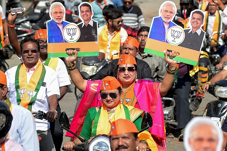 A supporter holds placards during a roadshow led by Maharashtra Chief Minister Devendra Fadnavis, unseen, on the last day of campaigning for the civic elections, in Nagpur. - | Photo: PTI