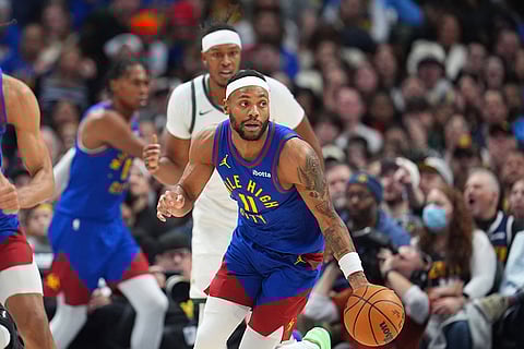 Denver Nuggets guard Bruce Brown, front, collects a loose ball as Milwaukee Bucks center Myles Turner pursues in the second half of an NBA basketball game in Denver.