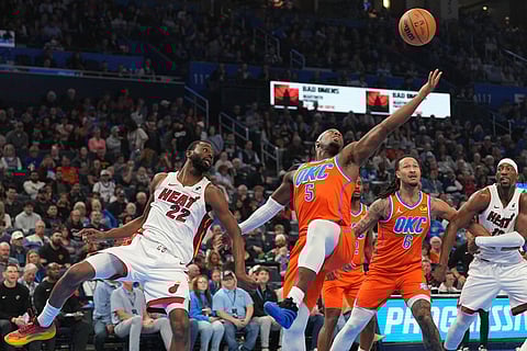 Oklahoma City Thunder guard Luguentz Dort (5) grabs a rebound in front of Miami Heat forward Andrew Wiggins (22) during the first half of an NBA basketball game in Oklahoma City.