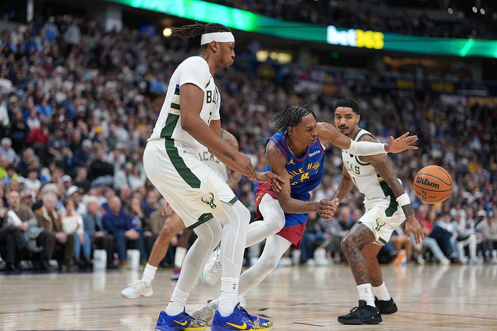Denver Nuggets guard Peyton Watson, center, loses control of the ball while driving between Milwaukee Bucks center Myles Turner, front, and guard Gary Harris in the second half of an NBA basketball game in Denver. - | Photo: AP/David Zalubowski