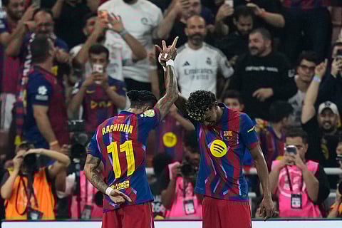 Barcelona's Raphinha, left, celebrates with teammate Lamine Yamal after scoring the opening goal during the Spanish Super Cup final soccer match against Real Madrid at King Abdullah Sports City Stadium in Jeddah, Saudi Arabia.