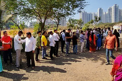 Police personnel stand guard as people wait in a queue to cast votes during the Navi Mumbai Municipal Corporation (NMMC) elections, at a polling station at Kopar Khairane, in Navi Mumbai, Maharashtra.