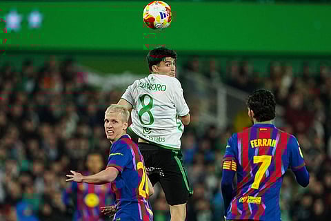 Rancing Santander's Aritz Aldasoro, center, heads for the ball next to Barcelona's Dani Olmo, left, during the Copa del Rey round of 16 soccer match between Racing Santander and Barcelona, in Santander, Spain.