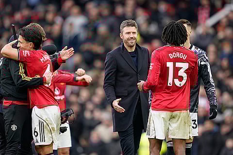Manchester United's head coach Michael Carrick, centre, greets Manchester United's Patrick Dorgu after the English Premier League soccer match between Manchester United and Manchester City in Manchester, England.
