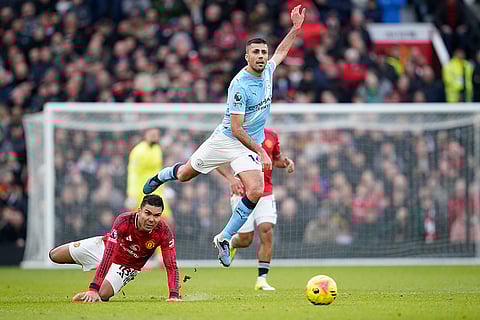 Manchester United's Casemiro, bottom, challenges for the ball with Manchester City's Rodrigo during the English Premier League soccer match between Manchester United and Manchester City in Manchester, England.