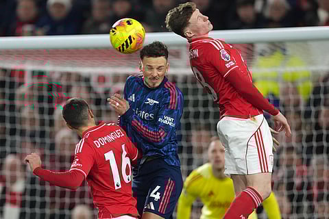 Arsenal's Ben White jumps for the ball with Nottingham Forest's Nicolas Dominguez and Elliot Anderson, right, during the English Premier League soccer match between Nottingham Forest and Arsenal in Nottingham, England.