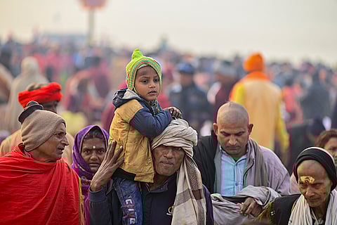 People arrive at the Sangam on a cold and foggy winter morning during the ongoing Magh Mela in Prayagraj.