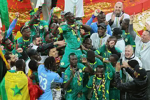 Senegal's Sadio Mane holds the trophy aloft as he celebrates with teammates after winning the Africa Cup of Nations final soccer match between Senegal and Morocco in Rabat, Morocco.