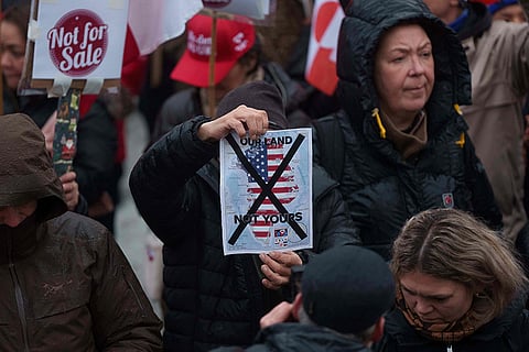 A man holds a map of Greenland covered in the American flag crossed out with an X during a protest against Trump's policy towards Greenland in front of the US consulate in Nuuk, Greenland.