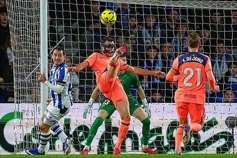Barcelona's Eric Garcia, centre, kicks the ball ahead of Real Sociedad's Mikel Oyarzabal, left, and Barcelona's Frenkie de Jong during the Spanish La Liga soccer match between Real Sociedad and Barcelona in San Sebastian, Spain.
