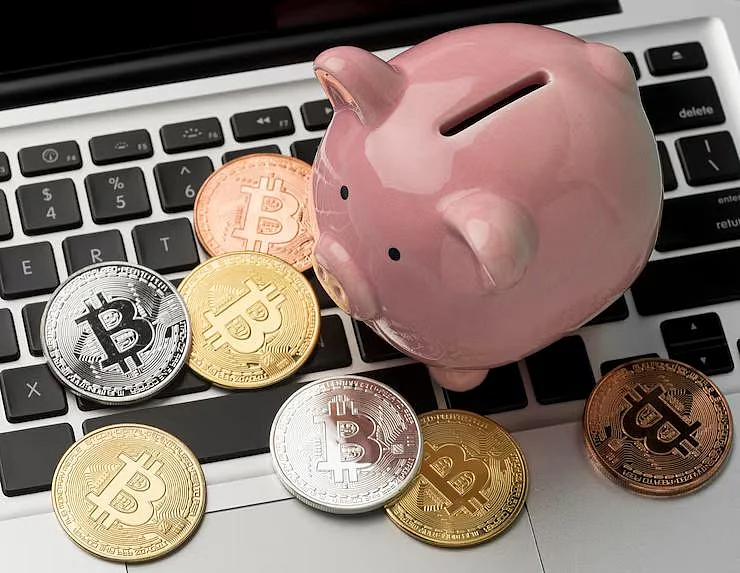 Pink piggy bank and Bitcoin coins on a laptop keyboard