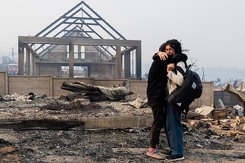 Mirtza Aguilera, right, and her daughter embrace in front of their home burned by wildfires in Tome, Chile.