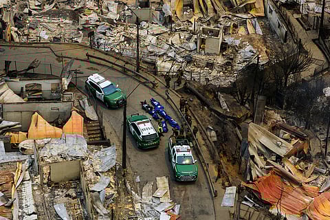 Police recover the bodies of people who died after wildfires swept through homes near Lirquen, Chile.