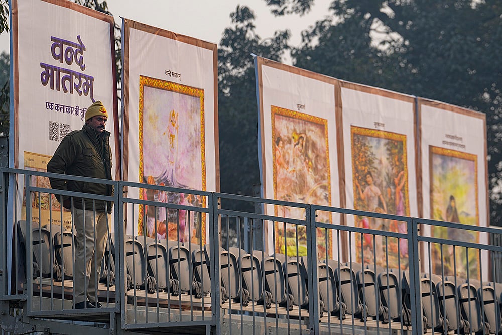 A police official stands guard near standees during rehearsals for the Republic Day Parade on a cold winter morning, in New Delhi. The sesquicentenary of 'Vande Mataram' will be the dominant theme of this year's parade, with enclosure backdrops along the Kartavya Path displaying old paintings illustrating the opening stanzas of the National Song and floral artworks at the main stage paying homage to its composer Bankim Chandra Chatterjee.  - | Photo: PTI/Kamal Kishore