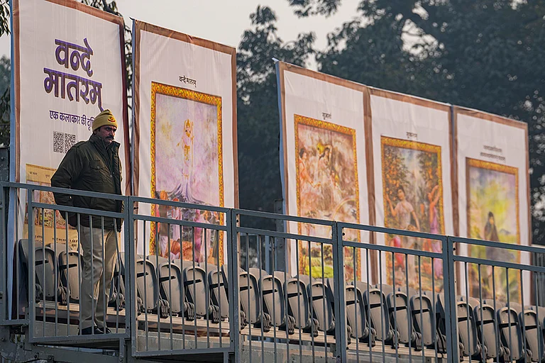 A police official stands guard near standees during rehearsals for the Republic Day Parade on a cold winter morning, in New Delhi. The sesquicentenary of 'Vande Mataram' will be the dominant theme of this year's parade, with enclosure backdrops along the Kartavya Path displaying old paintings illustrating the opening stanzas of the National Song and floral artworks at the main stage paying homage to its composer Bankim Chandra Chatterjee. - | Photo: PTI/Kamal Kishore