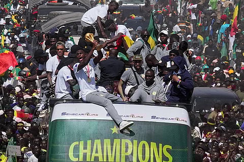 The Senegalese soccer team rides through thousands of cheering fans celebrating their victory in the Africa Cup of Nations soccer tournament, in Dakar, Senegal.