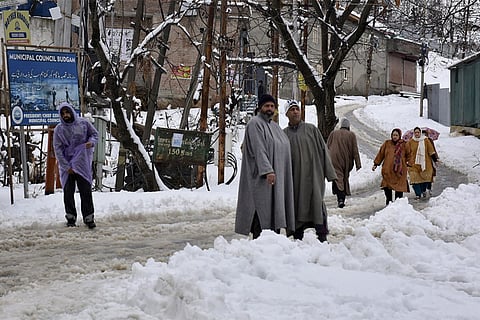 Residents navigate through fresh snowfall in Budgam, Jammu and Kashmir.