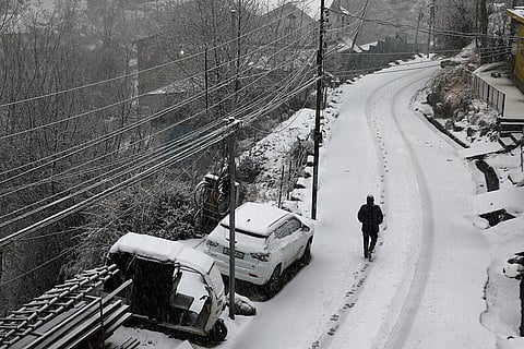 A man walks through snow amid fresh snowfall at Bhaderwah, in Doda district, Jammu and Kashmir.