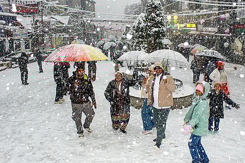 Tourists walk through a market area amid snowfall, in Manali, Himachal Pradesh.

