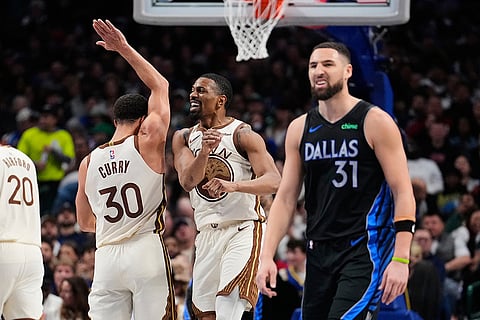 Golden State Warriors' Stephen Curry (30) and De'anthony Melton (8) celebrate a three-pointer by Melton as Dallas Mavericks' Klay Thompson walks up court in the second half of an NBA basketball game in Dallas.