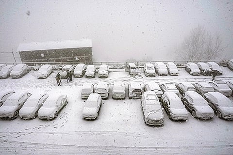 Vehicles lie covered under fresh snowfall in a parking area, in Shimla.