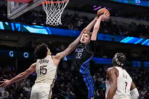 Dallas Mavericks forward Cooper Flagg (32) makes a move to the basket against Golden State Warriors' Gui Santos (15) and Buddy Hield (7) in the seond half of an NBA basketball game in Dallas.