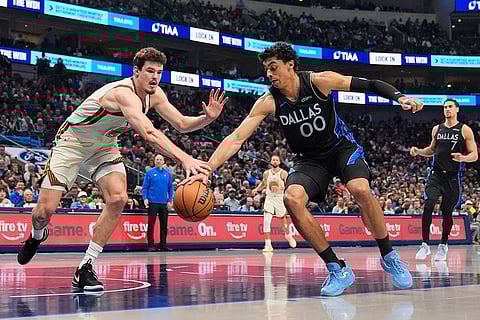 Golden State Warriors center Quinten Post (21) and Dallas Mavericks' Max Christie (00) compete for control of the ball in the first half of an NBA basketball game in Dallas.