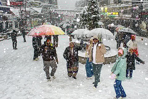 Tourists walk through a market area amid snowfall, in Manali, Himachal Pradesh.