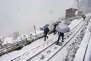 | Photo: PTI : People traverse a snow-covered rail track amid ongoing snowfall, in Shimla. The precipitation aligns with forecasts predicting up to 28 cm of snow on January 23, ending the region's dry spell under active western disturbances.